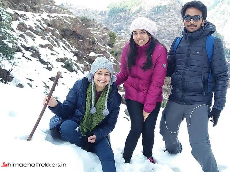 Friends posing in deep snow surrounded by pine woods in Barot Valley