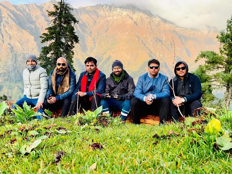 Group of friends resting together in a meadow with grand Himalayan slopes in the background