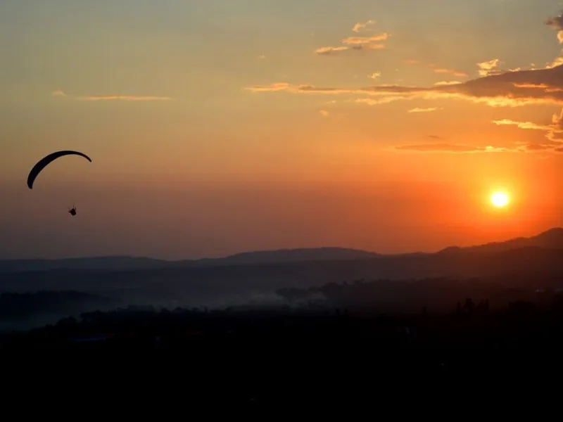 Silhouette of a paraglider floating in the sky against an orange sunset over Billing