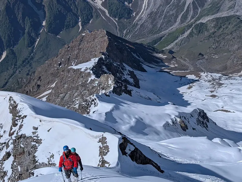 Mountaineer navigating a steep snowy ridge leading towards Friendship Peak summit