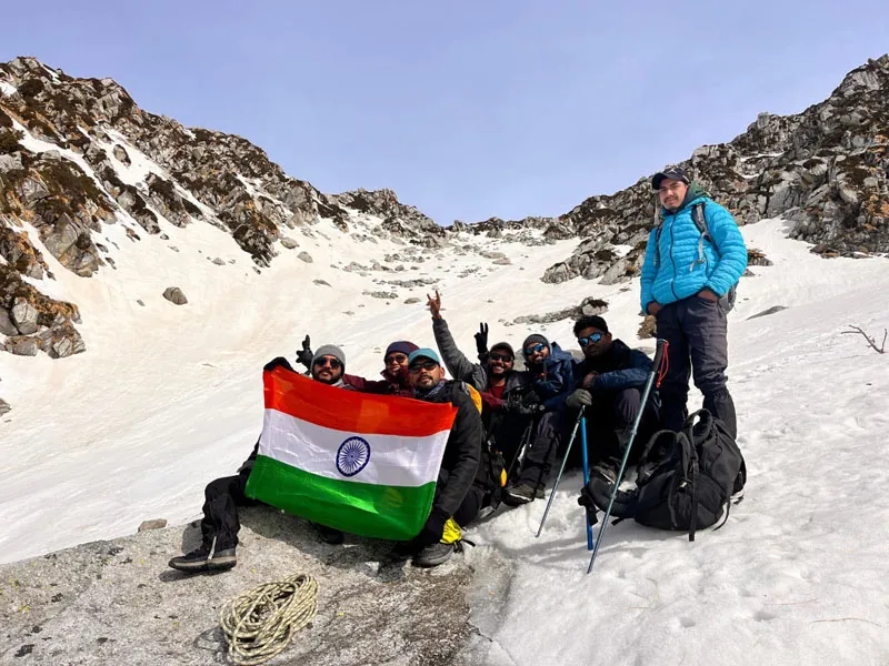 Trekking team holding the Indian tricolor flag on snow slopes at Indrahar Pass