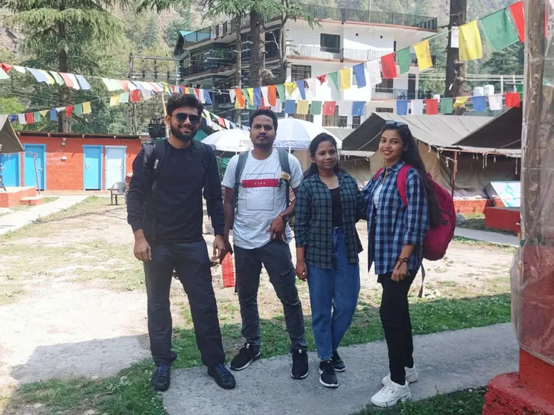 Group of friends posing in Kasol village courtyard decorated with vibrant prayer flags