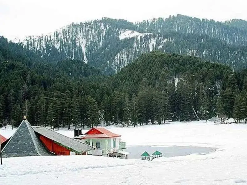 Khajjiar Lake cottage and alpine meadow completely covered in white winter snow surrounded by pine trees Dalhousie