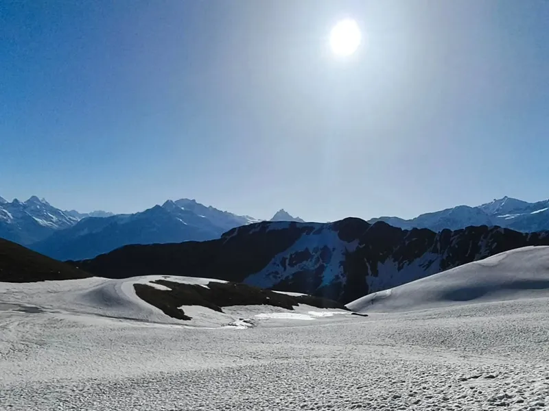 Bright sun shining over vast snowfields and mountain ridges at Sar Pass