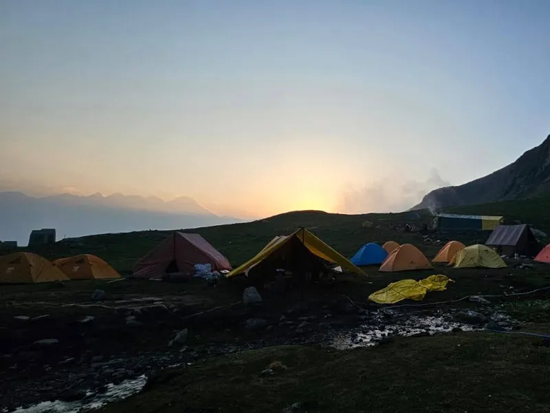 Alpine tents pitched at campsite during golden sunset over the Himalayan mountains