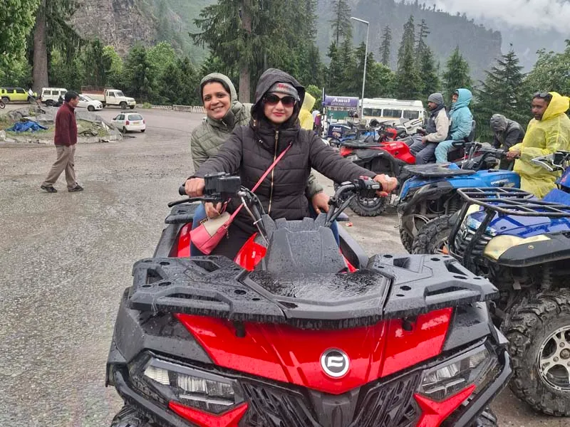 Tourists riding an all-terrain ATV quad bike on mountain adventure trail in Manali