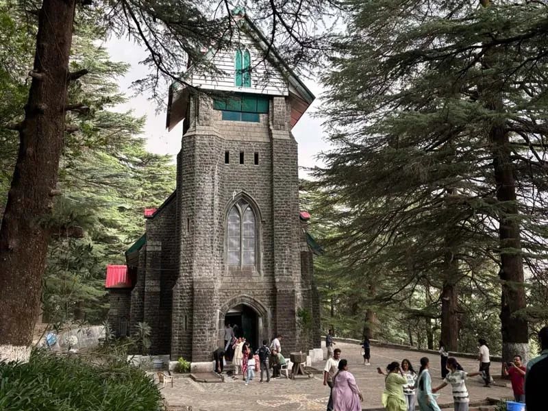Historic stone facade and bell tower of St. John in the Wilderness Church surrounded by deodars in Dharamshala